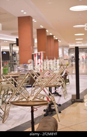 Stühle auf Tischen in einem spanischen Einkaufszentrum. Bar durch Coronavirus geschlossen. Das spanische Einkaufszentrum ist am 1. März 2021 geschlossen. Carcaixent, Valencia, Spanien. Stockfoto