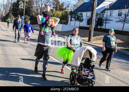 3-16-2019 Tulsa USA -Paar in St. Patricks Day T-Shirts Und Kostüme gehen in einem Wohltätigkeitslauf - sie schiebt Baby Kutsche und er trägt kleine Mädchen auf Stockfoto