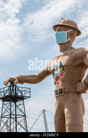 07 09 2020 Tulsa, USA Iconic Golden Driller - Riesenstatue des Ölfeldarbeiters in der Nähe der Route 66 in Oklahoma mit Harthut und Gesichtsmaske mit der Hand Stockfoto