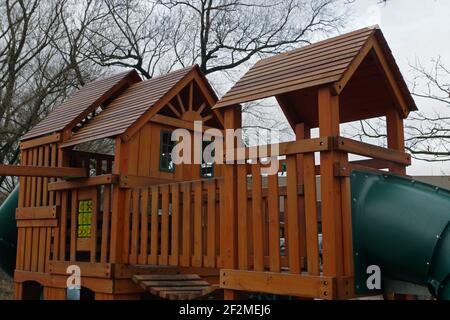 Upper part of playground is made of brown wooden planks with two green pipes slides on both sides and with green windows against the background of bra Stock Photo