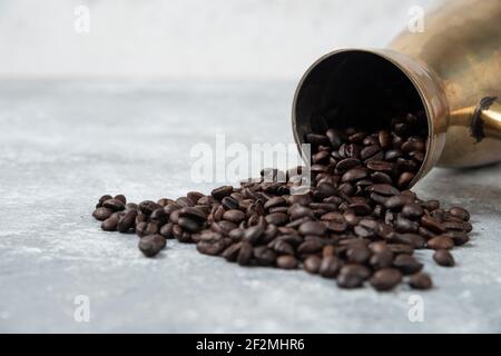 Kaffeemaschine voller gerösteter Kaffeebohnen auf Marmoroberfläche Stockfoto