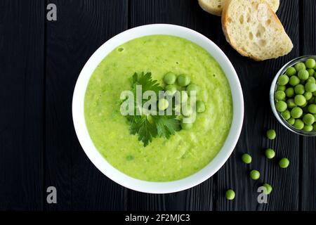 PEA Suppe in der weißen Schale auf dem schwarzen Holzhintergrund.Draufsicht. Stockfoto