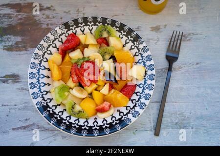 Natürlicher und gesunder Obstsalat mit Orange in einem Vintage-Teller, auf einer rustikalen Oberfläche. Gesunde Ernährung Konzept, Gesundes Leben. Blick auf den Zenith. Stockfoto