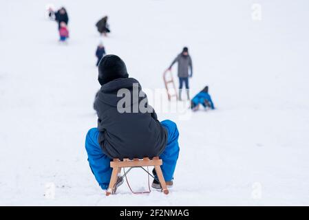 Ein Junge sitzt auf einem Schlitten und Rodeln. Stockfoto