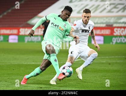 Augsburg, Deutschland. März 2021, 12th. Fußball: Bundesliga, FC Augsburg - Borussia Mönchengladbach, Matchday 25 in der WWK Arena. Mönchengladbachs Breel Embolo (l.) und Augsburgs Jeffrey Gouweleeuw kämpfen um den Ball. WICHTIGER HINWEIS: Gemäß den Bestimmungen der DFL Deutsche Fußball Liga und des DFB Deutscher Fußball-Bund ist es untersagt, im Stadion und/oder des Spiels aufgenommene Fotos in Form von Sequenzbildern und/oder videoähnlichen Fotoserien zu verwenden oder zu verwenden. Quelle: Matthias Balk/dpa/Alamy Live News Stockfoto