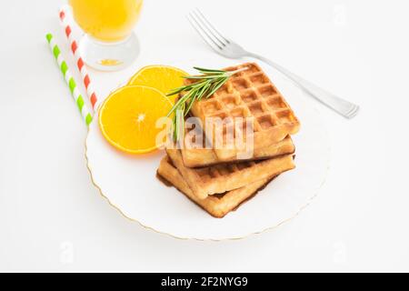 Frühstück mit belgischen Waffeln mit Rosmarin und Orangenscheiben. Nahaufnahme Stockfoto