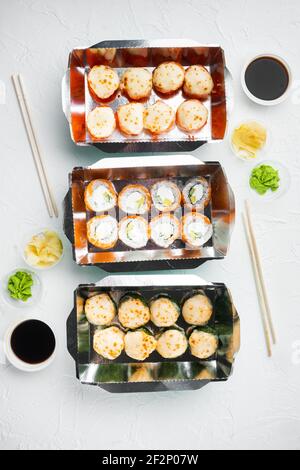 Sushi-Rollen im Takeaway-Container-Set, auf weißem Steinhintergrund, Draufsicht flach liegend Stockfoto