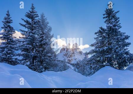 Italien, Venetien, Provinz Belluno, Auronzo di Cadore. Die Sonne geht zwischen Cadin della Neve und Cadin di Misurina in einer Winterlandschaft mit schneebedeckten Tannen, Cadini di Misurina, Dolomiten auf Stockfoto