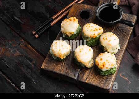 Gebackene Sushi-Rolle mit Garnelen und Kaviar-Kaviar-Kappe. Traditionelles Sushi-Restaurant mit Gerichten auf altem dunklen Holztisch Stockfoto