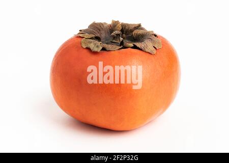 Nahaufnahme mit geringer Schärfentiefe einer reifen Kaki-Frucht auf einem schlichten weißen Hintergrund. Stockfoto