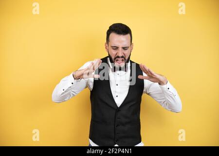 Junger Mann mit Bart in Fliege und Weste schreien Und laut schreien mit den Händen auf dem Mund Stockfoto