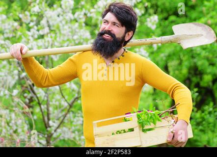 Landwirt im Frühlingsgarten. Gärtner mit Gartenschaufel. Lächelnder Mann, der sich auf die Pflanzung vorbereitet. Stockfoto