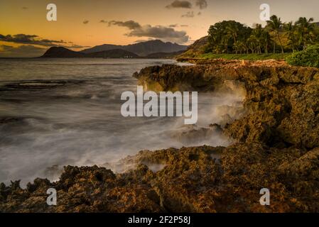 Spektakulärer Sonnenuntergang in Paradise Cove, Wellen des Pazifischen Ozeans, die auf vulkanischen Felsen entlang der idyllischen Küste, Kapolei, Oahu, Hawaii, USA, krachen Stockfoto