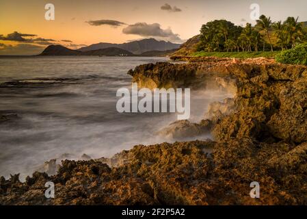 Spektakulärer Sonnenuntergang in Paradise Cove, Wellen des Pazifischen Ozeans, die auf vulkanischen Felsen entlang der idyllischen Küste, Kapolei, Oahu, Hawaii, USA, krachen Stockfoto