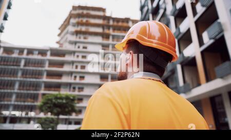 Thema ist der Gesundheitsschutz in Produktion und Bau. Kaukasischer Arbeiter in orange Uniform und Schutzmaske kn 95 setzt auf constructio Stockfoto