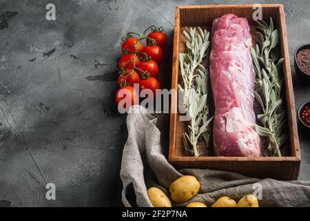 Rohes Schweinefilet mit Salbei-Set, in Holzkiste, auf grauem Steingrund, mit Copyspace und Platz für Text Stockfoto