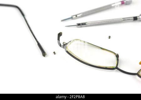 Gebrochene Brille und Schraubendreher auf grauem Hintergrund. Brillen Reparaturkonzept. Stockfoto