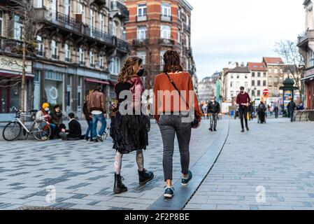 Saint-Gilles, Brüssel Hauptstadt Region - Belgien: 02 26 2021: Modische Mädchen gehen auf dem Parvis Marktplatz aus Stockfoto