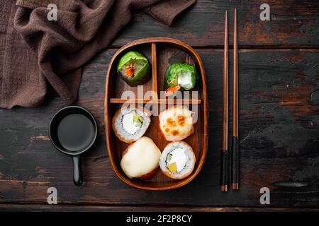 Hausgemachte Sushi Bento Box mit Sushi Rolls Set, auf altem dunklen Holztischhintergrund, Draufsicht flach liegend Stockfoto