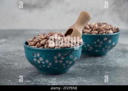 Rohe Bohnenkörner in Schalen auf Marmoroberfläche angezeigt Stockfoto