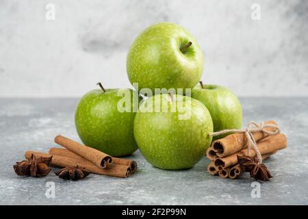 Ganze grüne Äpfel und Zimtstangen auf Marmor Hintergrund Stockfoto