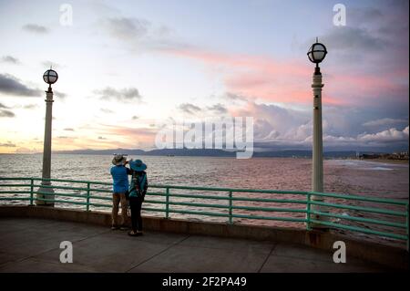 Paar fotografieren den dramatischen Sonnenuntergang vom Manhattan Beach Pier in Los Angeles South Bay. Stockfoto