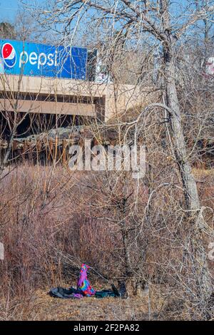 Lager für Obdachlose in Narrowleaf Willows entlang East Plum Creek mit Diesel-LKW auf der Interstate 25 im Hintergrund, Castle Rock Colorado. Stockfoto