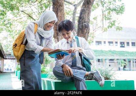 Ein hübscher Junge und verschleierte Mädchen in der indonesischen High School Einheitliches Lesebuch zusammen mit Kopierraum Stockfoto