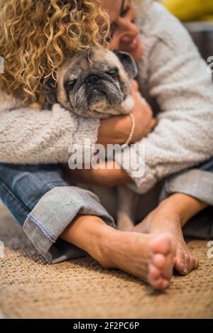 Haustiertherapie und Liebe Tier Hund Konzept mit einsamen Frau Zu Hause umarmt ihren eigenen Mops auf dem Boden - Brauntöne Bild der Menschen schärfen Lebensstil Stockfoto