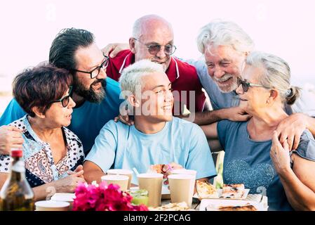 Gruppe von fröhlichen Freunden Familie genießen Essen und Mittagessen Feier Zusammen mit Spaß und Freundschaft - Konzept des verschiedenen Alters Jahre alte Menschen von Teenager bis Erwachsene und Senioren lächeln Und lachen Stockfoto