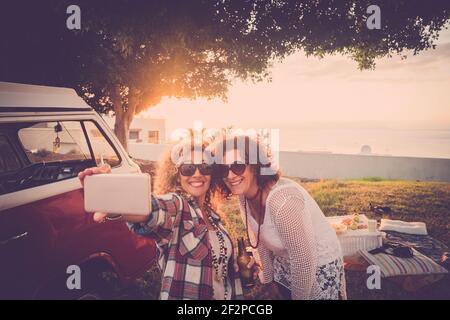 Paar weibliche Freunde genießen und Spaß haben zusammen nehmen Selfie im Freien - vintage roten Van und Sonnenlicht in Hintergrund - alternative Menschen Frauen in Freundschaft lächeln an der park in Freizeitaktivitäten Stockfoto