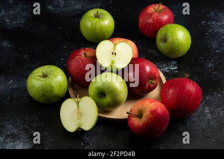 Ganze und in Scheiben geschnittene grüne und rote Äpfel auf Holzplatte Stockfoto