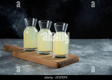 Drei Glaskannen mit frischem Zitronensaft auf einem hölzernen Platine Stockfoto