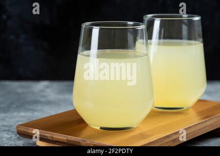 Zitrone frischer Saft in zwei Glas Becher auf einem hölzernen Platine Stockfoto