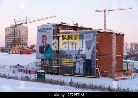 Deutschland, Sachsen-Anhalt, Magdeburg, Werbung für Immobilienkäufe bei einem Abbruchhaus. Dahinter sind Baukräne und ein Hochhaus. Stockfoto