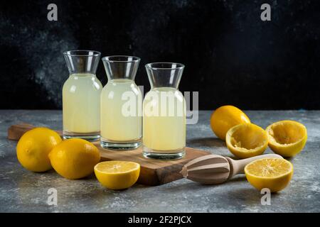 Drei Glaskannen Zitronensaft auf einem Holzbrett Stockfoto