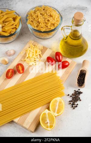 Rohe Vielfalt an Pasta, Öl und frischem Gemüse auf Marmor Hintergrund Stockfoto