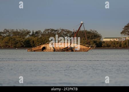 Eine verlassene Yacht liegt auf ihrer Seite, auf Grund im Hafen bei Ebbe. Stockfoto