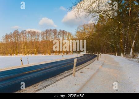 Landstraße Nr. K7222 im Winter in Deutschland, zwischen der Stadt Luckenwalde und dem kleinen Dorf Gottow, Gefahr der Glätte durch Schnee für Kraftfahrzeuge Stockfoto