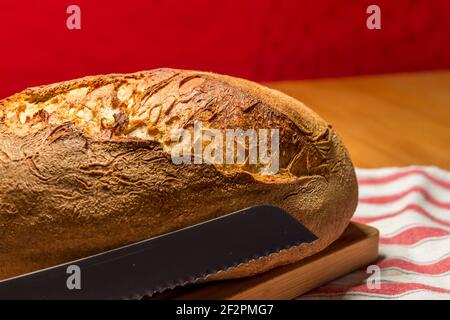 Frisches hausgemachtes Bio-Brot mit Brotmesser auf Holzplatte Stockfoto
