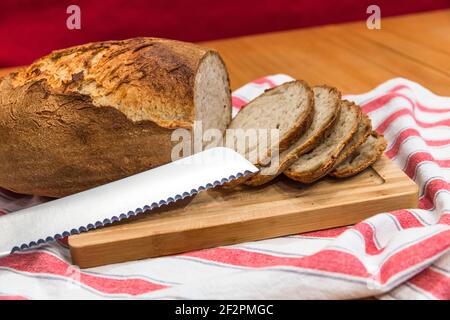 Frisches hausgemachtes Bio-Brot mit Brotmesser auf Holzplatte Stockfoto