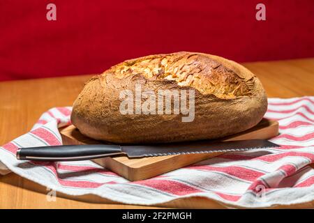 Frisches hausgemachtes Bio-Brot mit Brotmesser auf Holzplatte Stockfoto