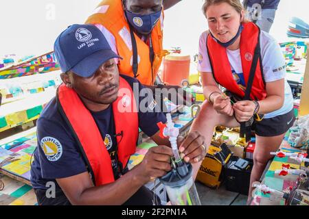 Kisumu, Nyanza, Kenia. März 2021, 9th. Bahati Mayoma montiert Mikroplastik-Tiefenwassersammler, während die Freiwilligen der FlipFlopi Expedition sich während der Untersuchungen anschauen.Bahati Mayoma, eine tansanische Forscherin, die sich auf aquatische Ökologie und Umweltmanagement spezialisiert hat, untersucht das Ausmaß der Mikroplastik-Verschmutzung im Viktoriasee. Quelle: James Wakibia/SOPA Images/ZUMA Wire/Alamy Live News Stockfoto