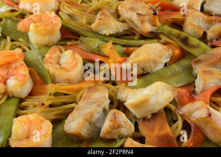 Nahaufnahme von Garnelen und Hühnerauflauf mit Karotten, Schneeerbsen und Pasta Stockfoto