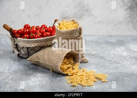 Rustikale Körbe von Pasta mit Kirschtomaten auf Marmor Hintergrund Stockfoto