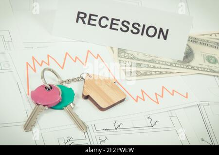 Home Schlüssel, Inschrift Rezession, Währungen Dollar und Abwärtsgraphen, die die Finanzkrise des Immobilienmarktes durch Coronavirus verursacht. Rot Stockfoto