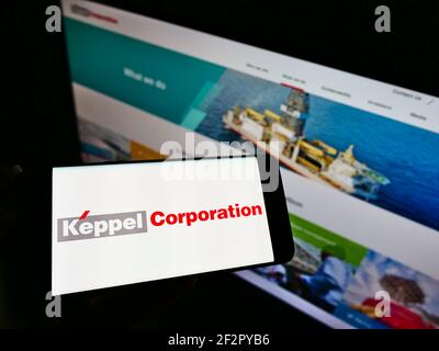 Person, die Smartphone mit Logo des singapurischen Konglomerats Keppel Corporation auf dem Bildschirm vor der Website hält. Konzentrieren Sie sich auf die Telefonanzeige. Stockfoto