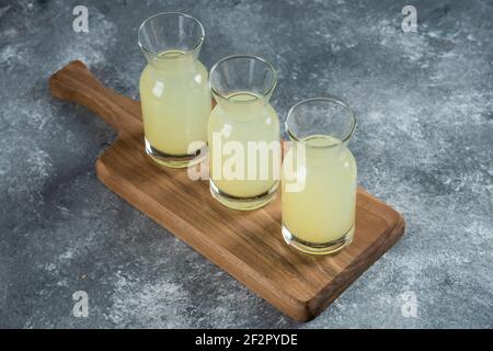 Drei Glaskrüge mit frischer Limonade auf einem Holzbrett Stockfoto