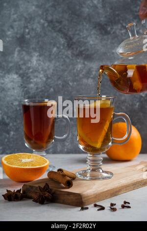 Aus transparentem Glas Teekanne gießen Tee in Glas Becher Stockfoto