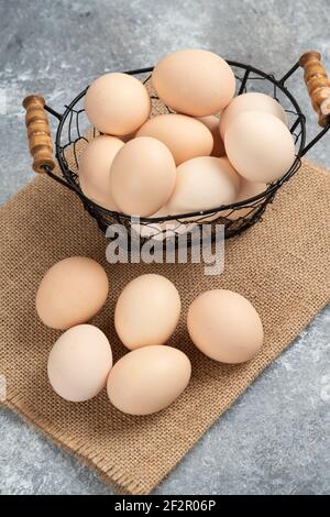 Korbkorb mit rohen Bio-Eiern auf Marmorboden Stockfoto